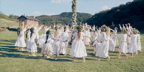 From the film MIDSOMMAR, A bunch of young women in white dresses running up toward a maypole